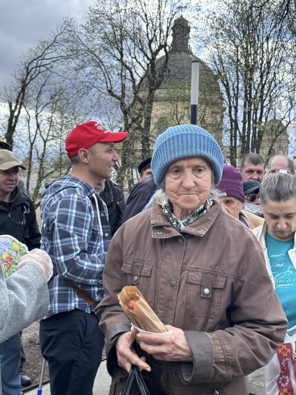 An Elderly Ukrainian Woman Holding A Hot Dog From The Distribution An Elderly Ukrainian Woman Holding A Hot Dog From The Distribution