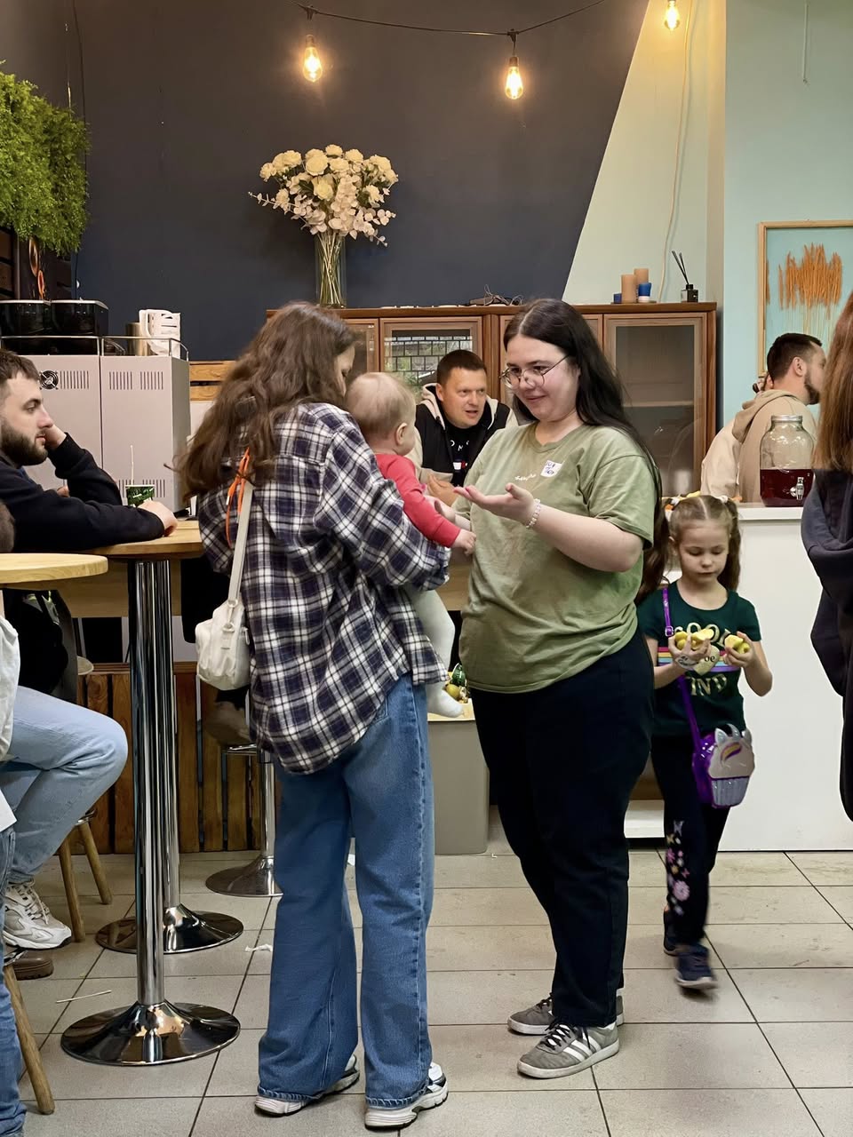 A Couple Mothers Conversing While One Of Them Holds A Baby A Couple Mothers Conversing While One Of Them Holds A Baby